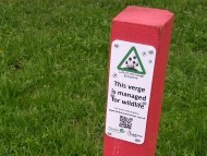 Sign used to mark the managed verges Post with a sign on it against a background of grass