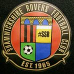 Shamwickshire Rovers club badge Shield with a representation of the bridge at the top and then the club colours quartered with a football and #SSR, encircled by the club name, and Est. 1965S